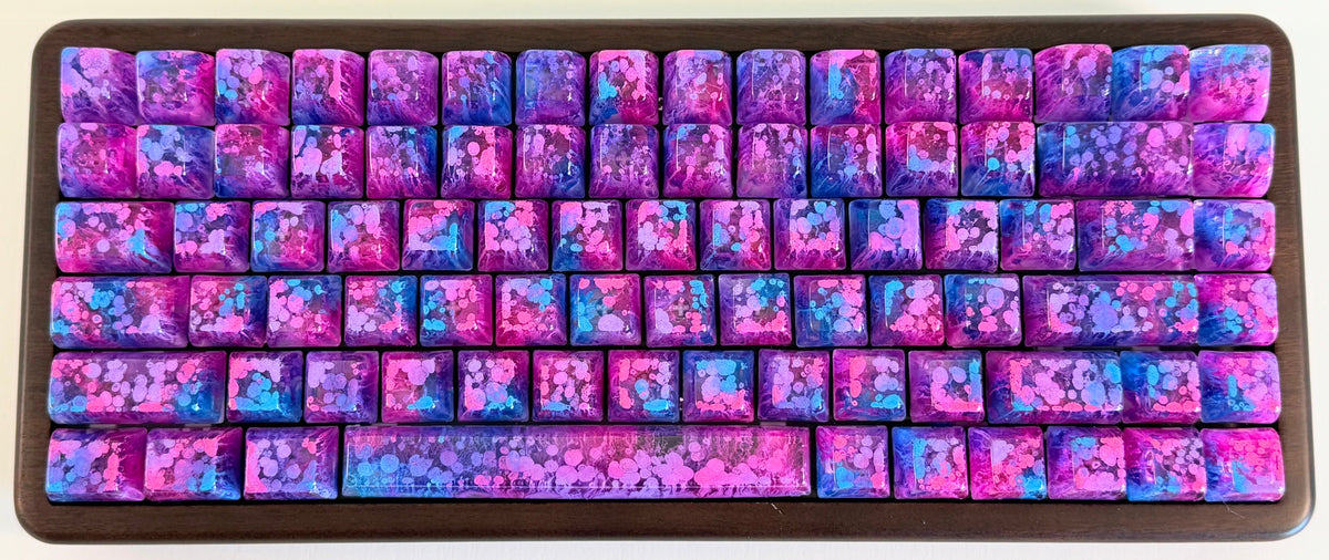 Keyboard with pink, blue, and purple keycaps on a white background